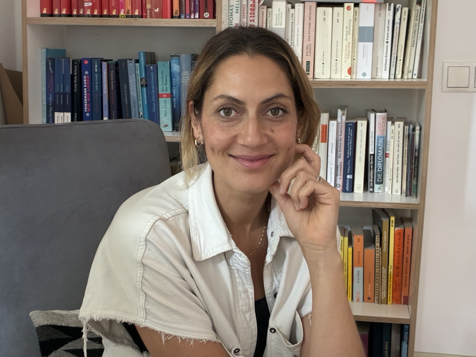 Franca Casabonne sitzt lächelnd vor einem Bücherregal